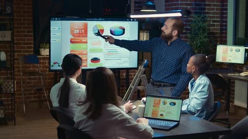 Business Team Analyzes Charts During an Evening Meeting