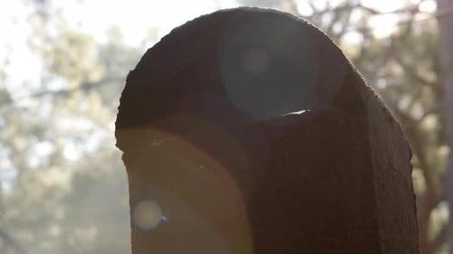 Vista cercana de la chimenea de piedra negra del horno cubierta de hollín de la que sale el sol un humo blanco acre