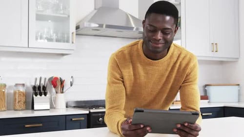 Young Adult Man Using Tablet in Modern Kitchen