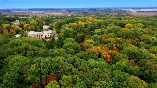 Historical palace in the beautiful green park. Cityscape and agricultural fields at backdrop.