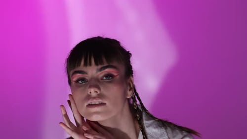 Stylish Woman Posing with Dramatic Makeup on Pink Background