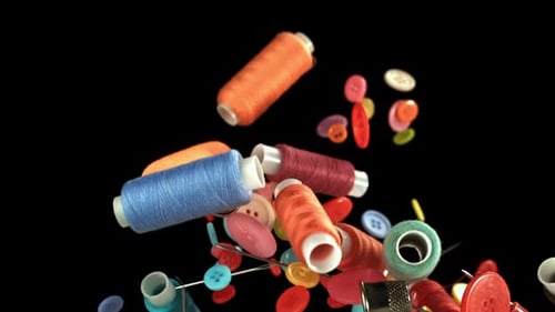 Colorful Thread Spools and Buttons Floating on Black