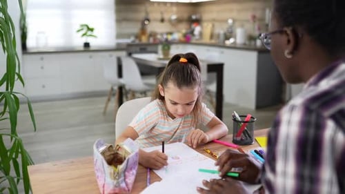 Girl Drawing at Table with Adult in Home