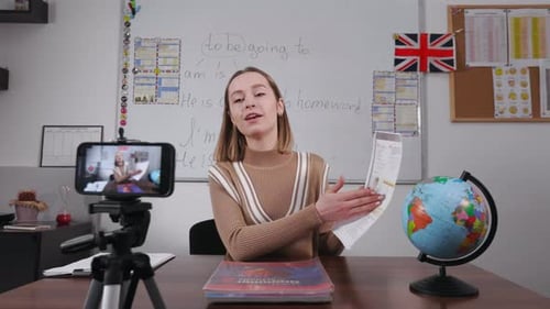 Female Tutor Using Cell Phone to Stream Lesson at Work