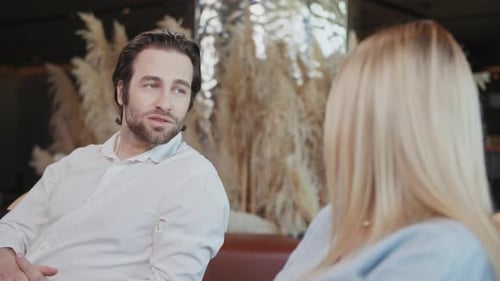 Attractive Man and Beautiful Woman in a Cafe Talking Discussing Smiling Sitting Modern Interior Have