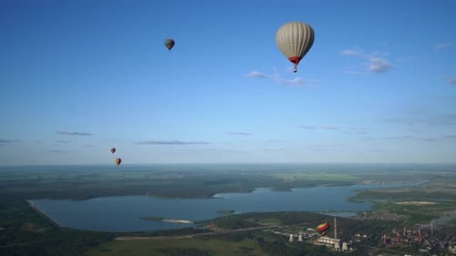 Hot Air Balloons are Levitating in the Sky Over Countryside with Green Hills and River