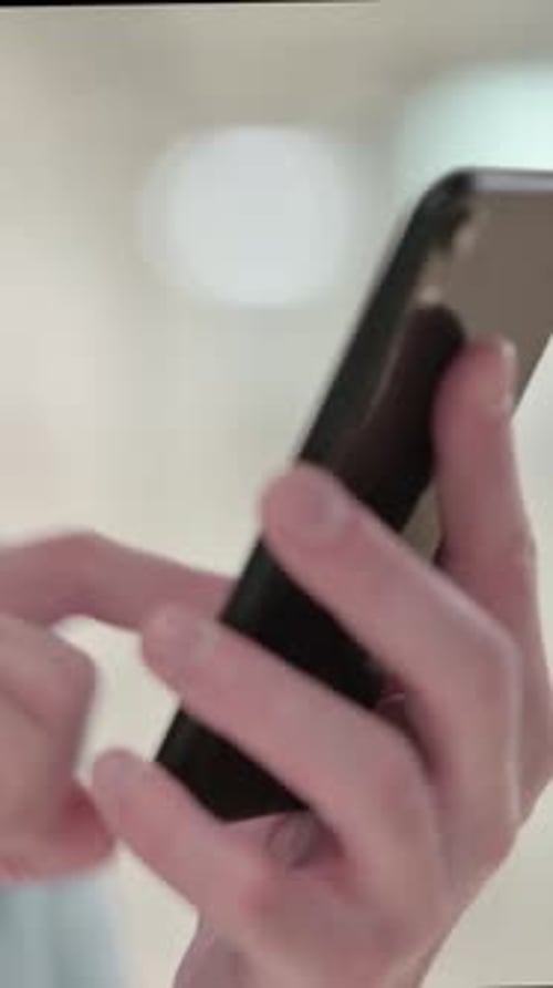 Hands Scrolling on Mobile Phone Screen Indoors