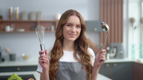 Smiling woman holding cooking tools in modern kitchen
