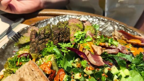 Gegrilltes Rindfleisch mit Sauce, Pesto, Spinat und Grünkohlsalat auf einem Teller, Nahaufnahme, Gesundes Essen