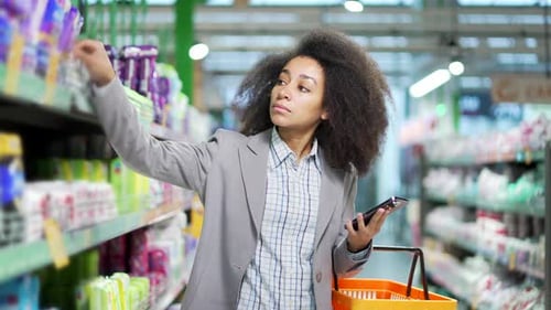 Young woman shopping in a supermarket walking choosing products in a grocery store. Happy female