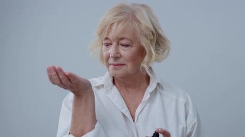 Smiling Senior Woman Sprays Perfume on Her Wrist