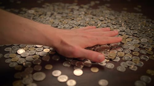 Pile of Coins on Table with Hand