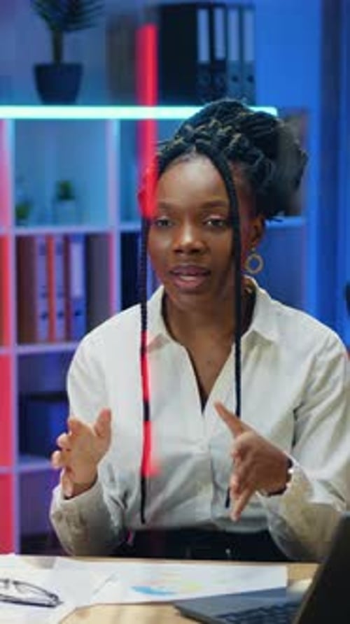 Adorable African Woman Office Worker in White Blouse Sitting in Front of Video Camera in Workroom