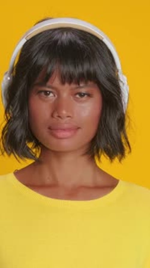 Jeune femme avec un casque aime la musique sur fond jaune vif