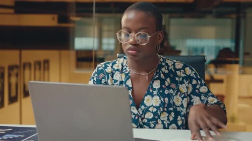 Young Black Businesswoman Working on Laptop and Writing Down Notes