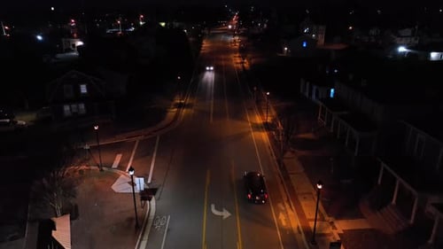 Cars on street in american neighborhood at night. Illuminated glowing lights of streetlamps. Descend