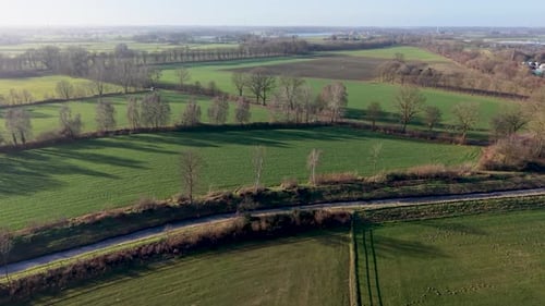 Aerial landscape showcasing a patchwork of lush green fields, winding country roads, and rows