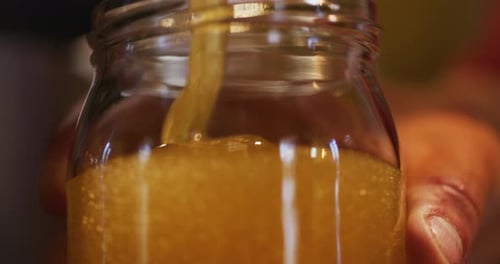 CloseUp of Pouring Fresh Organic Honey Into Jar