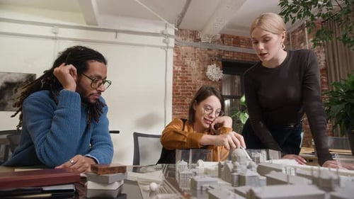 Diverse Architectural Design Team Observing 3D Layout on Table in Modern Office
