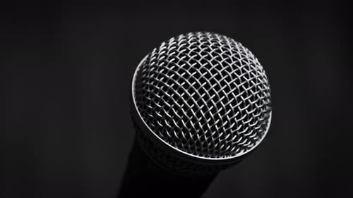 Dynamic Handheld Microphone Rotates on a Black Background CloseUp
