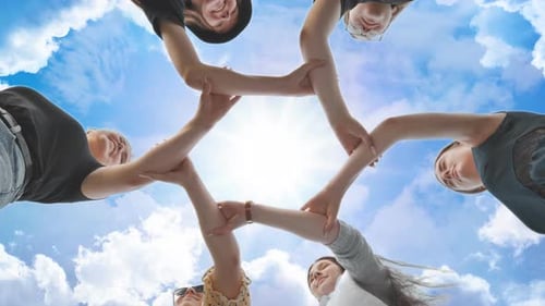 Freunde legen ihre Hände am Handgelenk zusammen und bilden einen Kreis vor dem Hintergrund eines fabelhaften Himmels