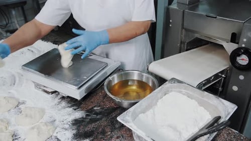 Professional Baker Weighing Raw Dough Pieces on Electronic Scales in Industrial Bakery