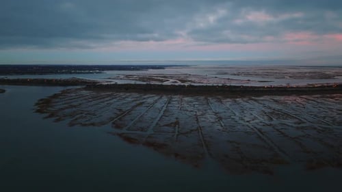 An aerial view over the salt marsh in Freeport, NY during a cloudy sunset. The camera truck left and