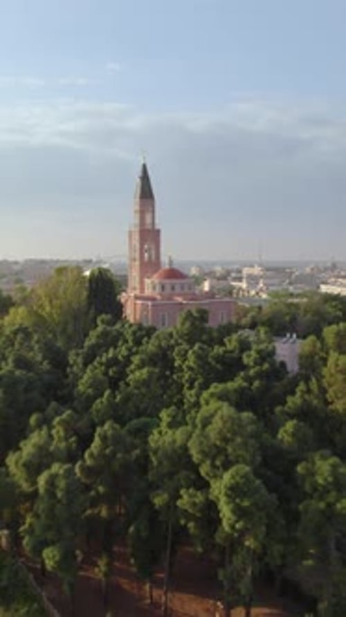Pink Russian church sanctuary framed by urban greenery - aerial drone movement, Tel Aviv