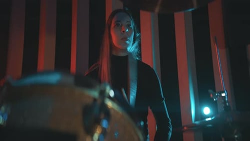 Female Drummer Plays in Red and Blue Lit Room