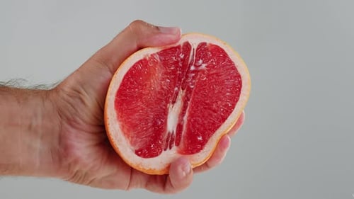 Hand Squeezes Pink Grapefruit Half