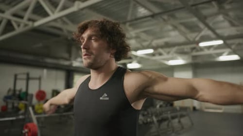 Muscular Man Doing Arm and Wrist Warming Exercises in Gym