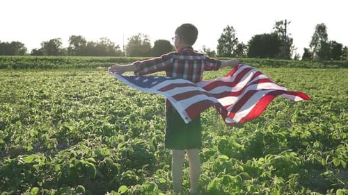 Child Holds American Flag in Grassy Field
