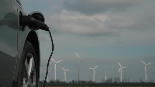 Electric Car Charging With Wind Turbines in Background