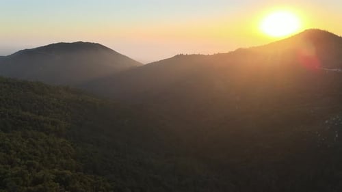 Aerial drone panorama of the sun setting above the forested hills in California. Autumn season, the