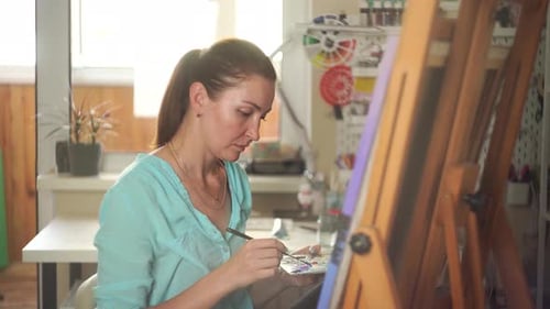 Canvas Artistry: Brunette Artist Paints in Creative Studio