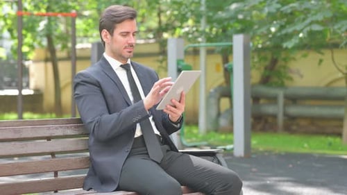Young Businessman Using Digital Tablet while Sitting on Bench