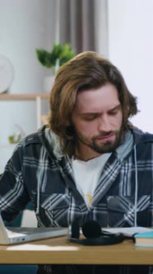 Man Works on Laptop at Home at Desk