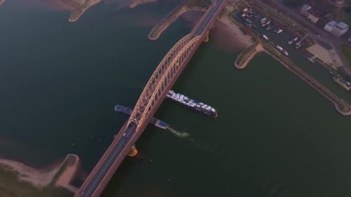 Aerial view of drone capturing cargo ship with cars on river sunset
