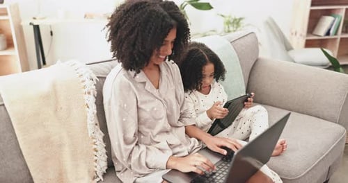 Woman and Child Using Technology on Couch Indoors