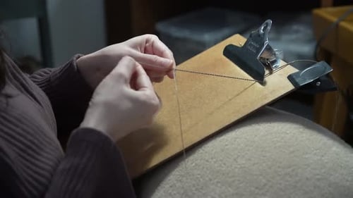 Close Up of Thread Knotting on Clipboard