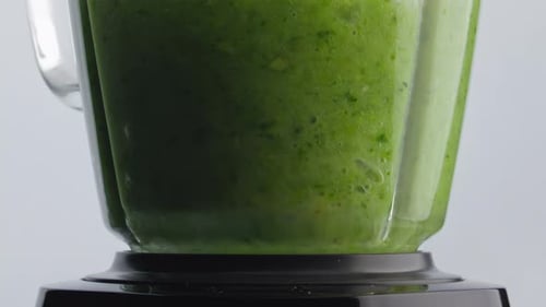 Grüne Smoothie-Mischung, die in einer Mixschüssel in Superzeitlupe gemischt wird