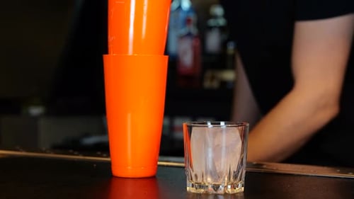 Male Bartender Working in a Bar While Making Cocktail Bartender Putting a Piece of Ice Into a Glass