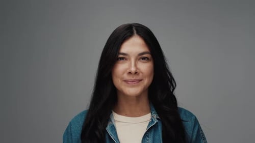Studio Portrait of Young Woman Opening Eyes Looking at Camera and Smiling Happy