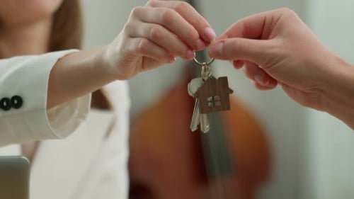 Homeowner Receives the Key to an Apartment in a New House From a Realtor in a Modern Office Happy