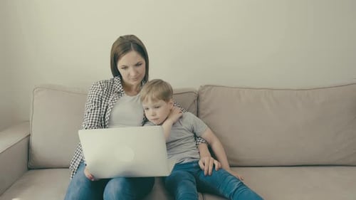Woman and Child Using Laptop on Sofa