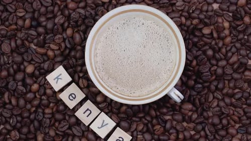 Cup of Coffee on a Background of Coffee Beans with the Word Kenya Outlined
