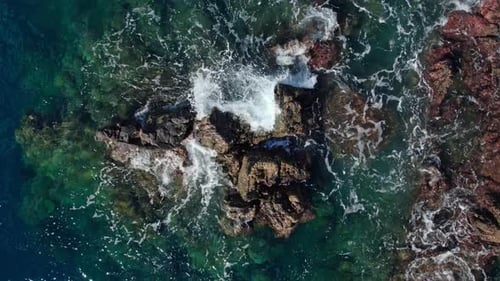 Slow Motion Aerial Orbit of Cinematic Turquoise Ocean Waves and Coastal Rocks