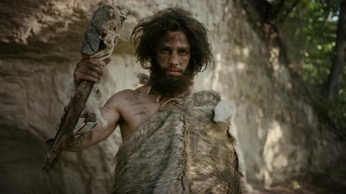 Primitive Man Poses with Club in Rocky Landscape