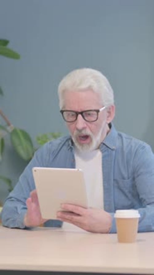 Senior Man Using Tablet at Table with Coffee