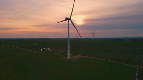 Large Wind Turbines with Blades in Field Aerial View Bright Orange Sunset Blue Sky Wind Park Drone